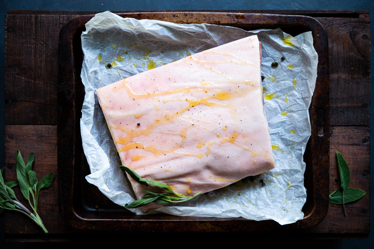 A great pork belly cut in a roasting tray with olive oil and seasoning on the skin