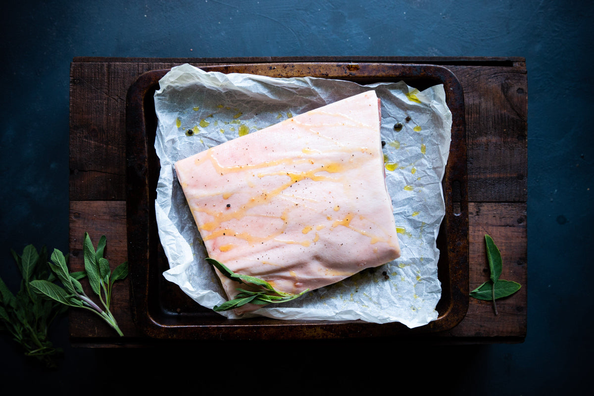  A great pork belly cut in a roasting tray with olive oil and seasoning on the skin